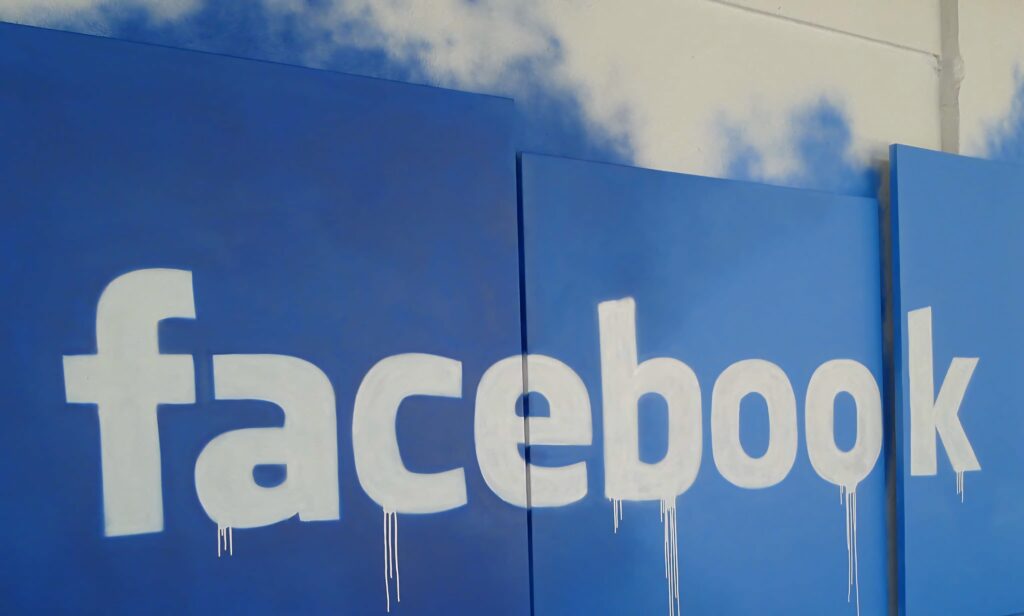Facebook wallpaper with white logo and blue background featuring artistic paint drips and spray effects