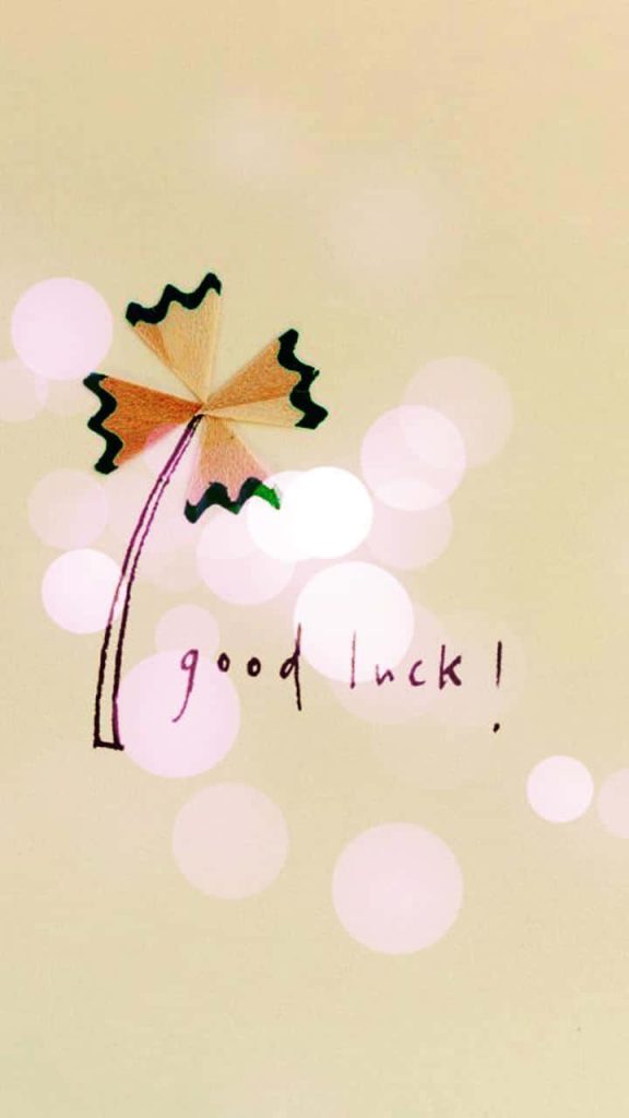 Creative four-leaf clover made of pencil shavings on cream background with good luck text wallpaper
