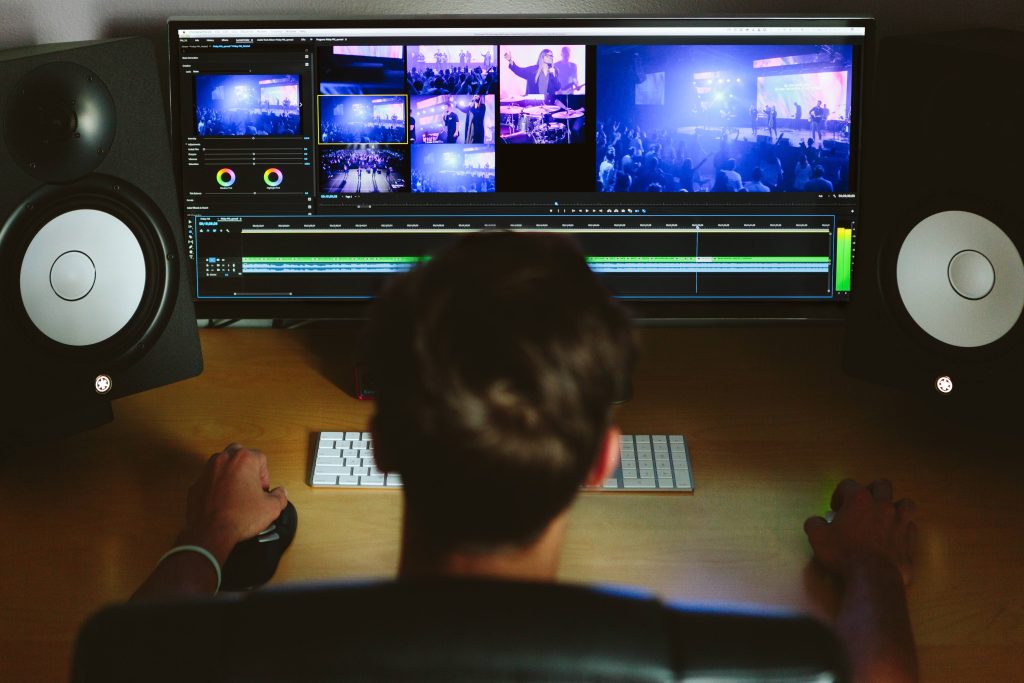 Man editing video in Adobe Premiere Pro with Yamaha studio monitors in dark creative workspace Wallpaper