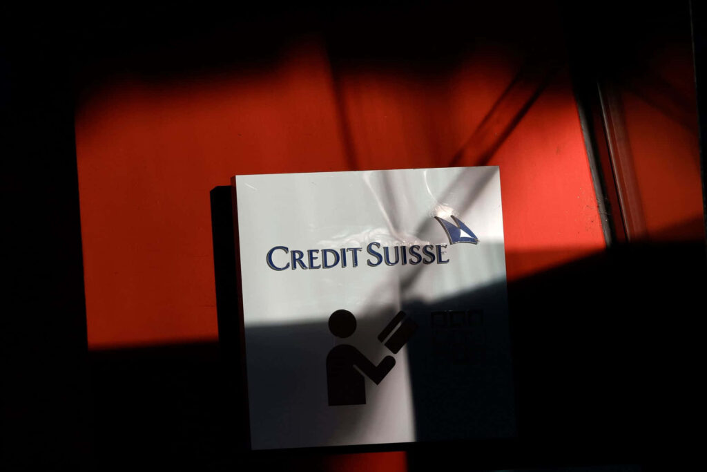 Credit Suisse logo on white sign with ATM icon dramatic shadows red and black background wallpaper