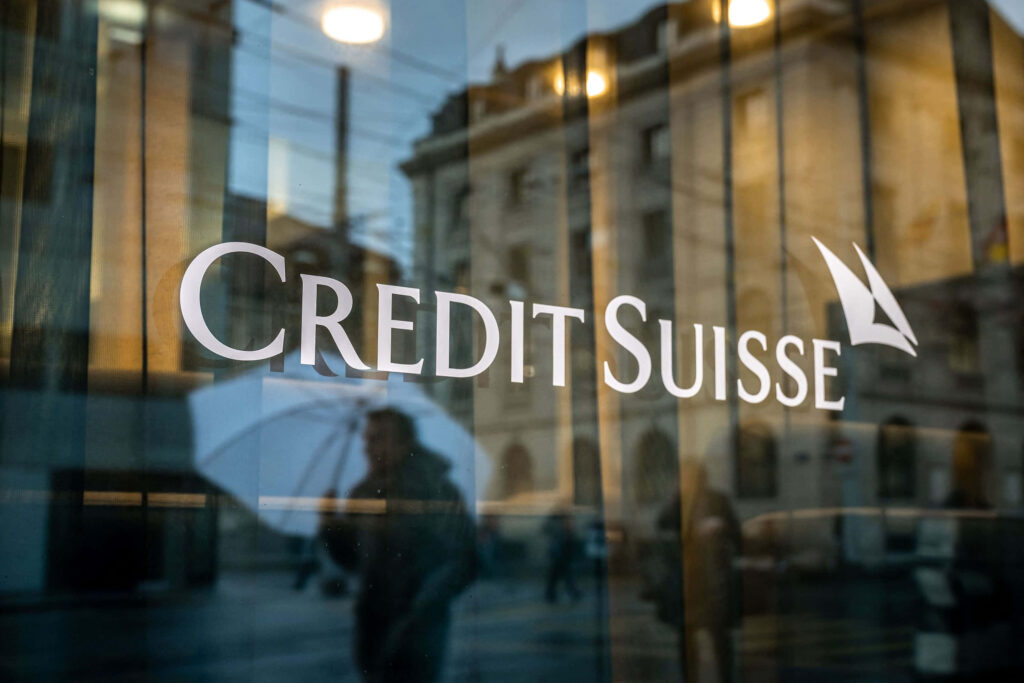Credit Suisse logo on glass building with urban reflections and blurred figures blue tones wallpaper