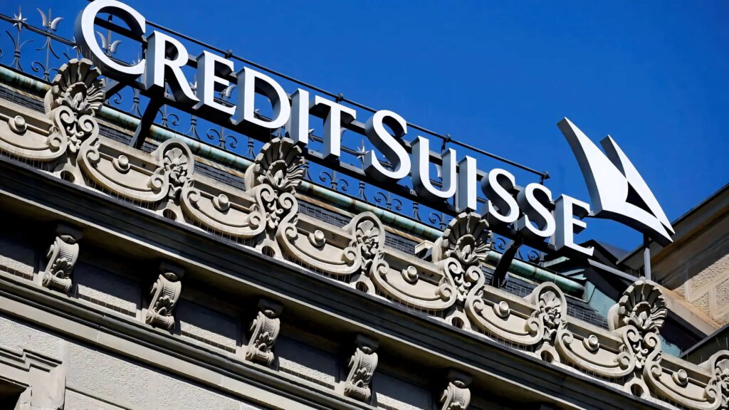 Credit Suisse logo on classical historic building under vibrant blue sky showcasing prestige and stability Wallpaper