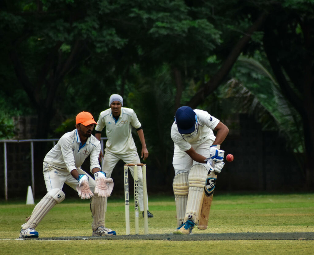 Clashing Teams: The Battle of Blue and Orange in Cricket Wallpaper