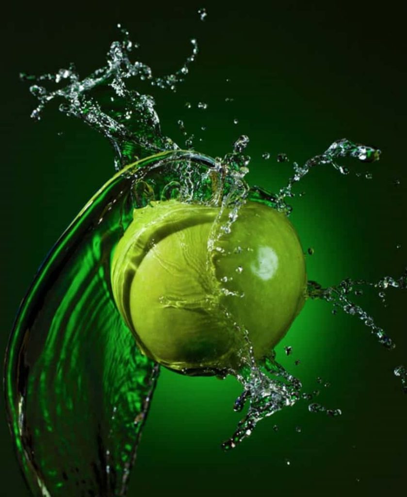Crisp green apple with dynamic water splash on deep green gradient wallpaper background