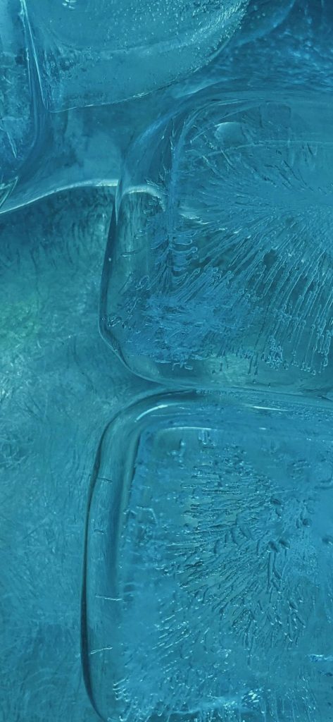 Macro shot of crystalline frozen ice cubes in cool blue tones with sharp icy textures background Wallpaper