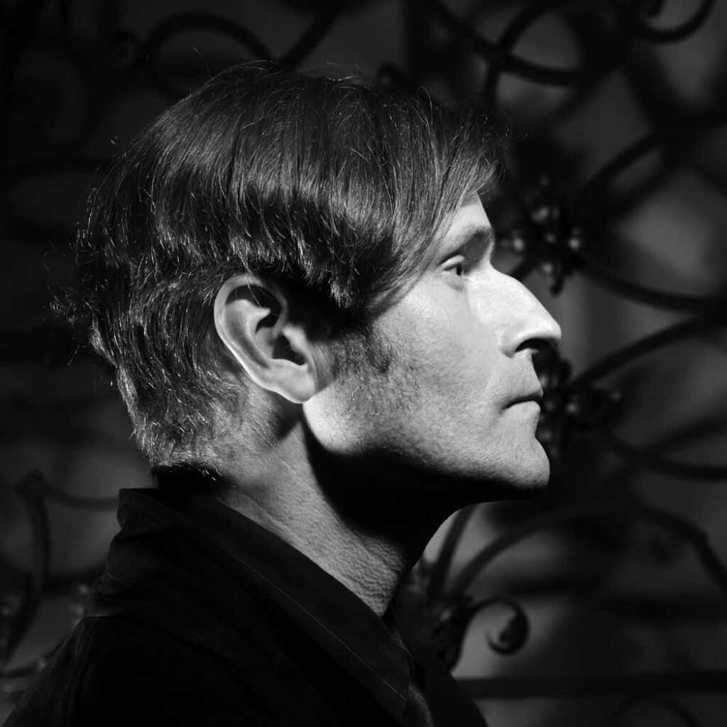 Black and white Crispin Glover portrait with dramatic lighting and abstract cinematic background wallpaper