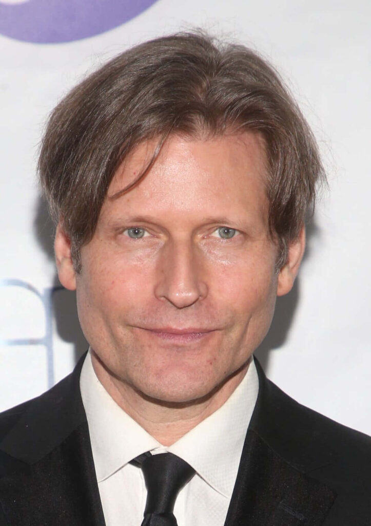 Crispin Glover portrait in dark suit with distinctive hairstyle against soft background wallpaper