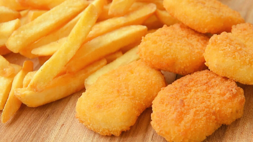 Golden crispy chicken nuggets and French fries on wooden surface vibrant food wallpaper background