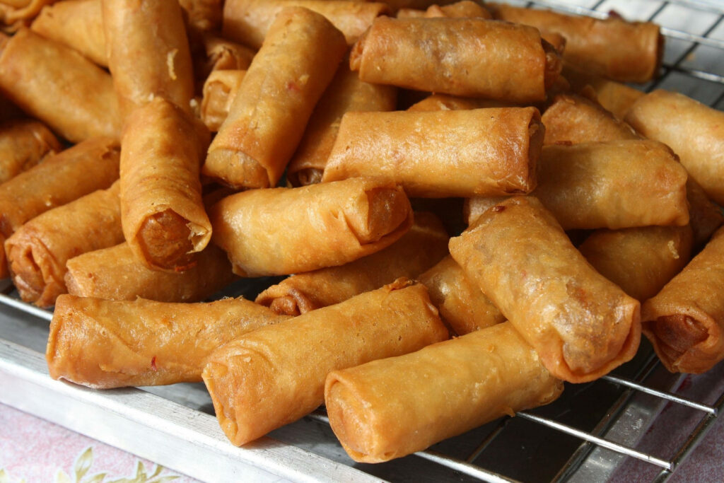 Golden crispy egg rolls on wire rack fresh fried savory snacks delicious appetizer display Wallpaper