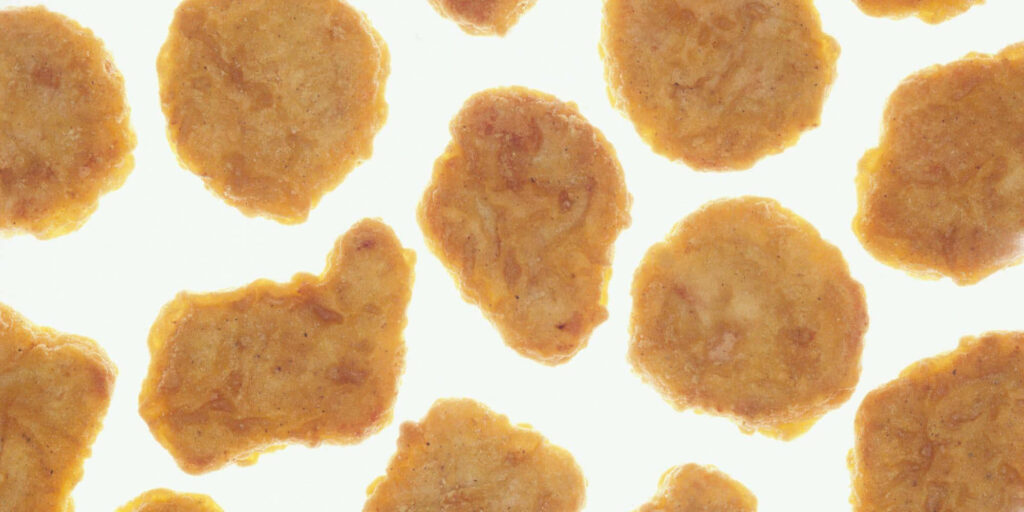 Close-up of crispy golden-brown chicken nuggets with crunchy coating on a light background Wallpaper