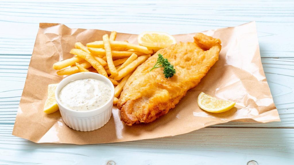 Crispy golden fish and chips with tartar sauce lemon wedges and parsley on rustic blue table Wallpaper