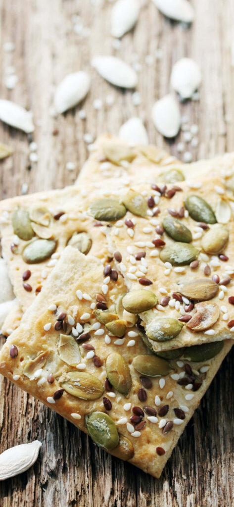 Close-Up of Crispy Seed-Topped Crackers on Rustic Wood Wallpaper