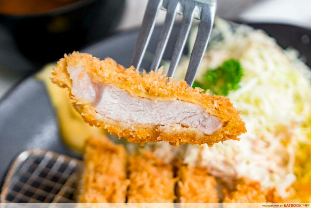 Crispy Tonkatsu Slice on Fork with Shredded Cabbage Background Wallpaper