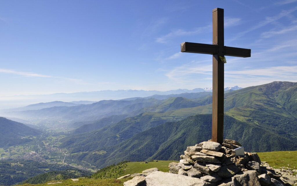 Majestic Summit: A Breathtaking Landscape with a Cross Embracing Towering Mountains Wallpaper