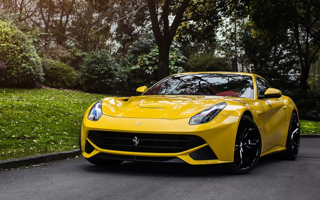 Exuding Power and Elegance: The Classic Yellow Ferrari F12 Berlinetta Captivates as it Speeds Down the Road Wallpaper