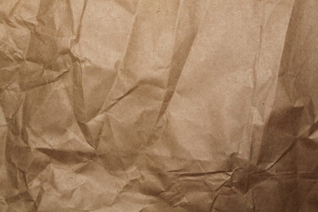 High-resolution crumpled brown paper wallpaper with rich texture and soft dramatic lighting