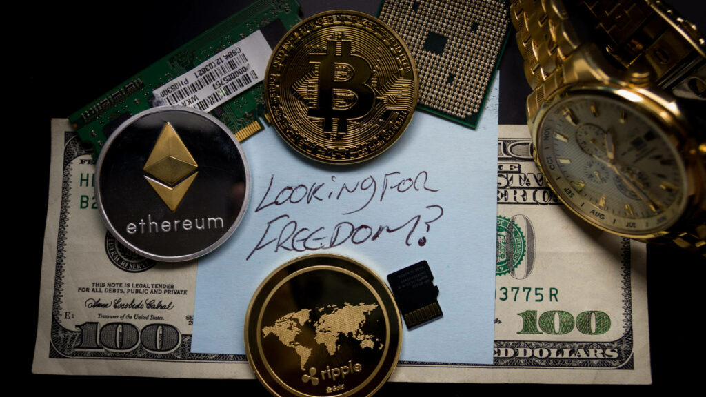 Ethereum Bitcoin and Ripple coins on hundred dollar bill with freedom note and gold watch background Wallpaper