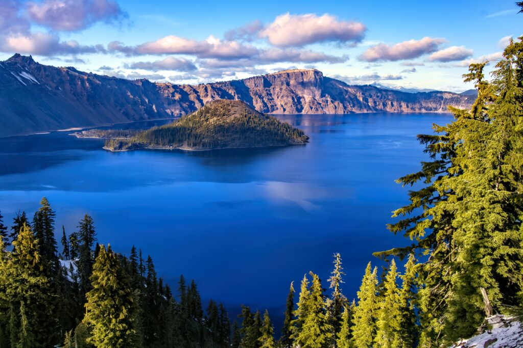 Crystal blue bay with rugged mountains and evergreen trees bathed in golden sunlight wallpaper