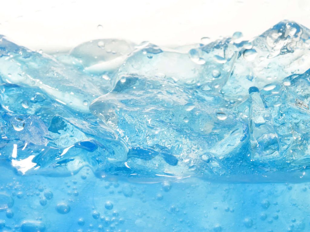 Close-up of crystal-clear ice cubes in sparkling blue liquid with bright bubbles background Wallpaper