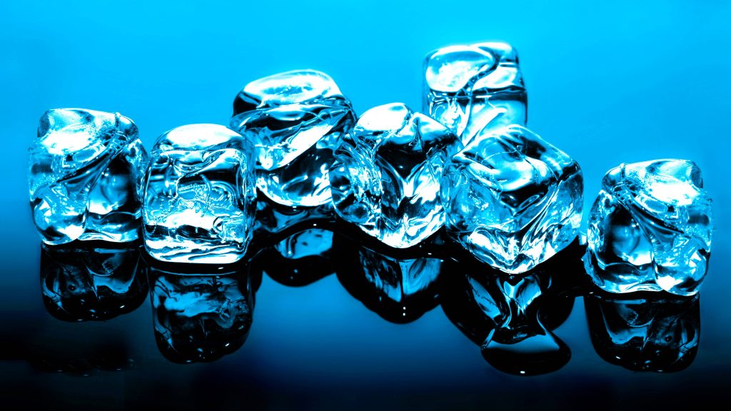 Crystal-clear ice cubes on reflective surface with vibrant blue gradient background wallpaper