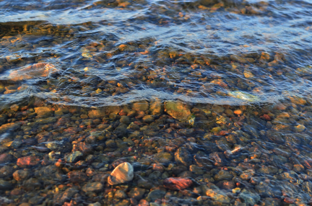 Crystal clear water rippling over colorful stones nature wallpaper background tranquil scene