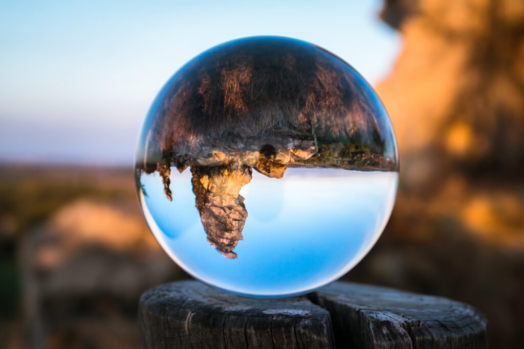 Crystal glass bowl on tree stump reflecting vivid Konigstein mountain landscape in warm tones Wallpaper