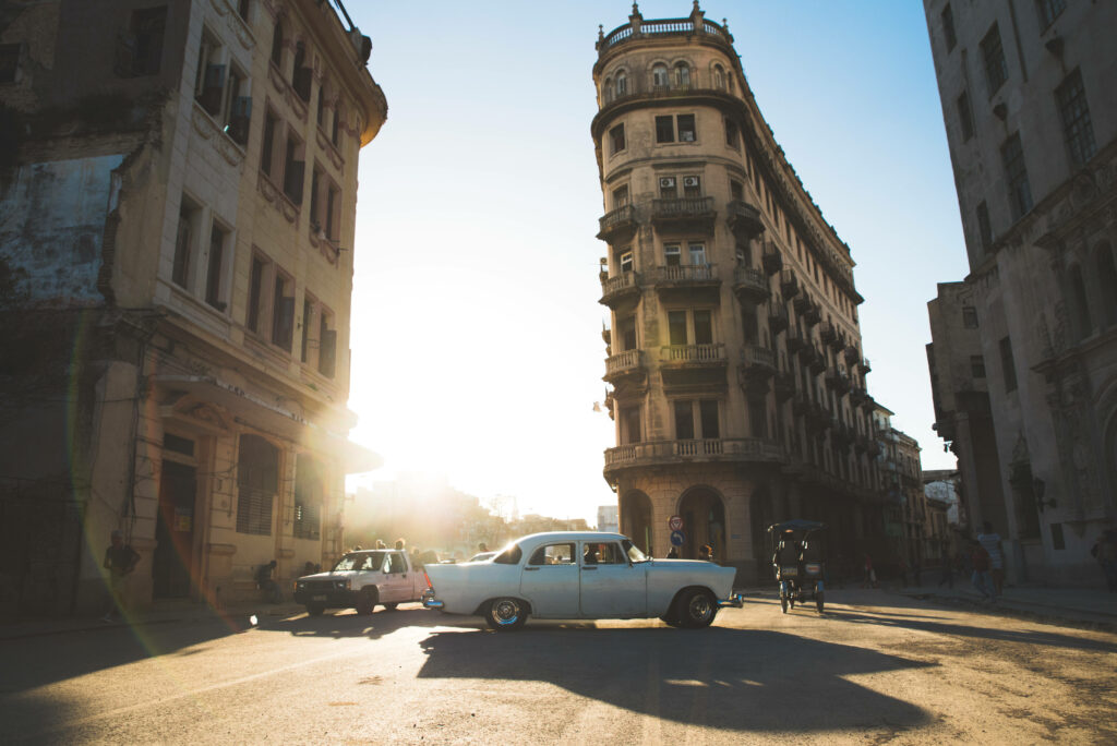 Vibrant Cuba: Classic Car on Sunlit Street - Wallpaper Background