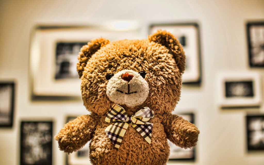 Cuddly Delight: A Close-up Snapshot of an Adorable Teddy Bear Amidst a Toy Wonderland Wallpaper