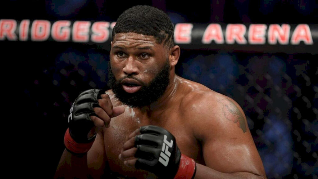 Curtis Blaydes focused in UFC octagon intense stance dramatic lighting dark arena background Wallpaper