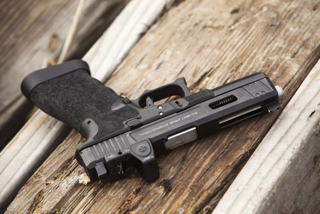Customized Salient Arms Glock 17 with silver barrel and Trijicon RMR on rustic wood background Wallpaper