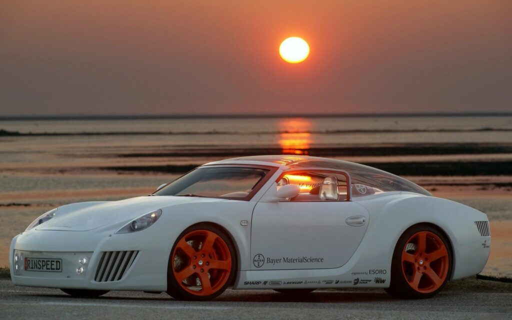 Custom White Sports Car with Orange Rims at Sunset Shoreline Wallpaper