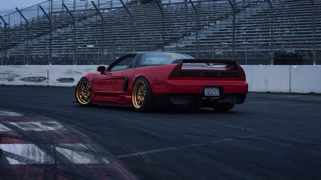 Customized red Honda NSX on racetrack with gold wheels and aggressive spoiler under overcast sky Wallpaper