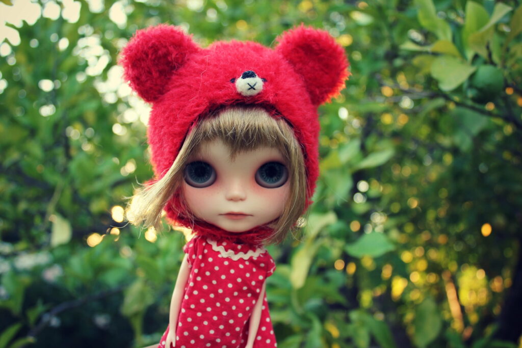 Blythe doll in fuzzy red teddy bear hat red polka dot dress dreamy green nature wallpaper