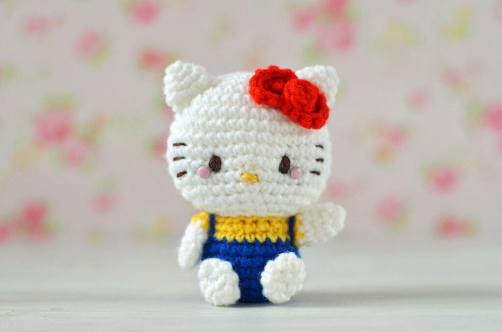 Cute Hello Kitty Crocheted Doll with Floral Wallpaper Background