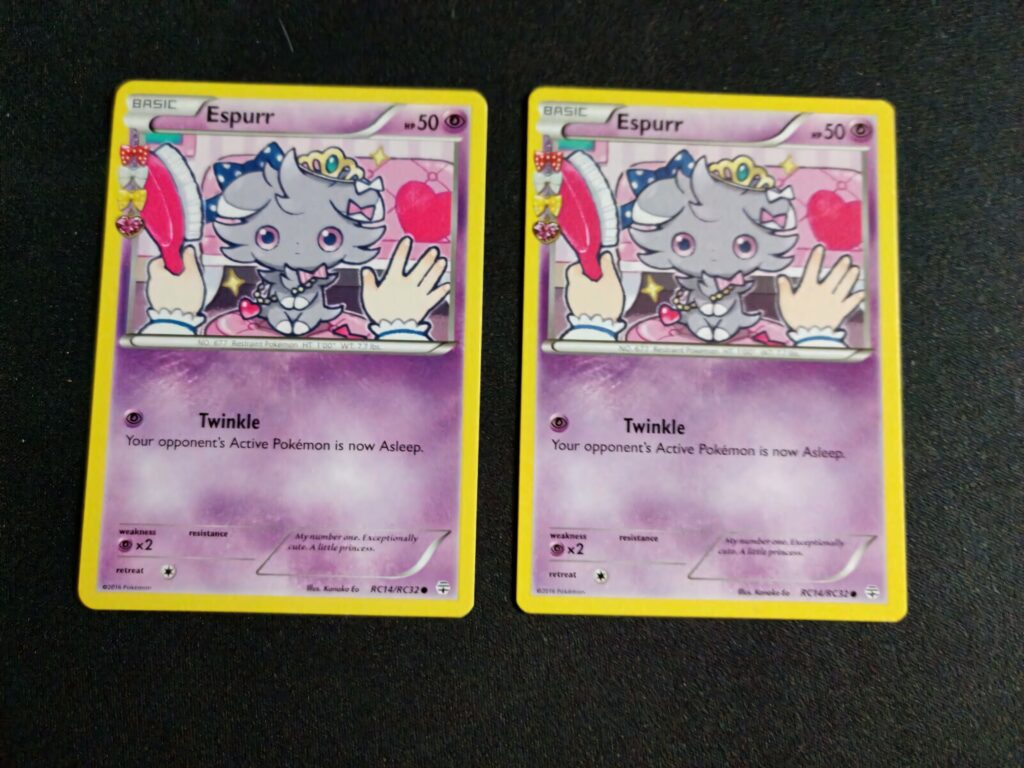 Two pastel Espurr Pokemon cards with cute whimsical design on black textured wallpaper background