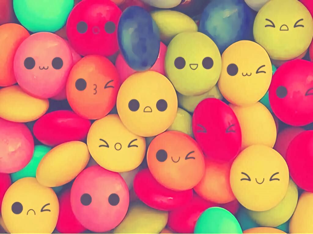 Playful kawaii wallpaper with colorful round candies showing cute cartoon faces and emotions