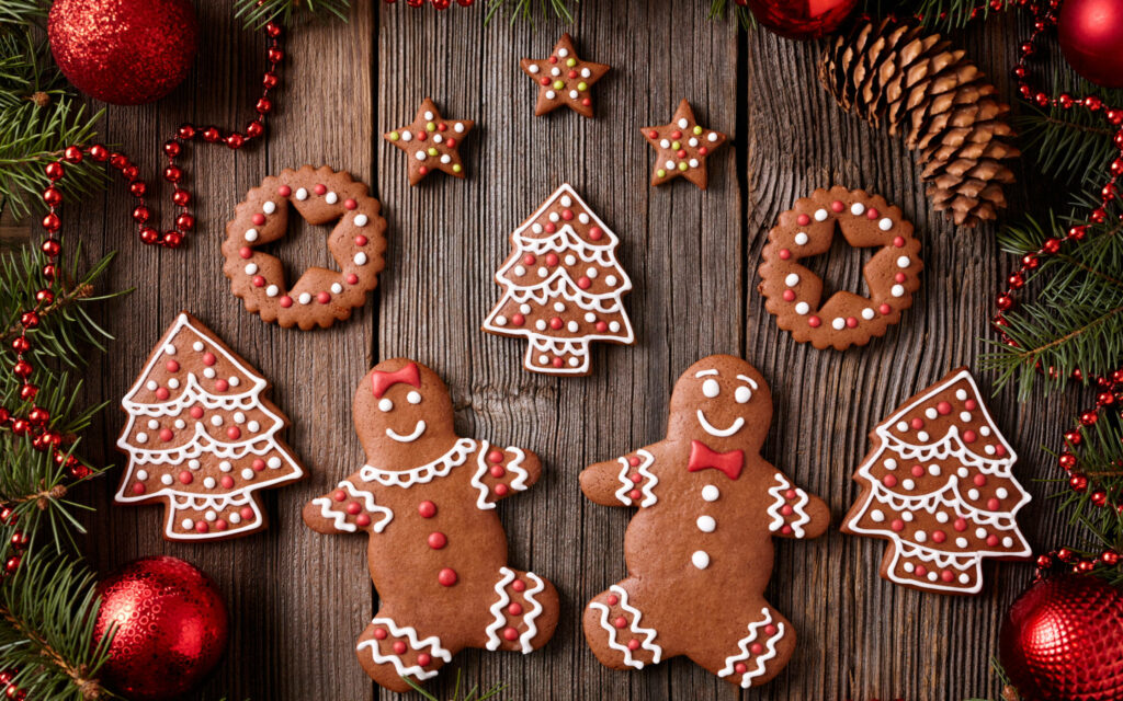 Delectable Delights: Festive Christmas Cookie Medley with Gingerbread Fun, Shapely Trees, and Stellar Stars, showcased on a Rustic Wooden Table Adorned with Christmas Trimmings Wallpaper