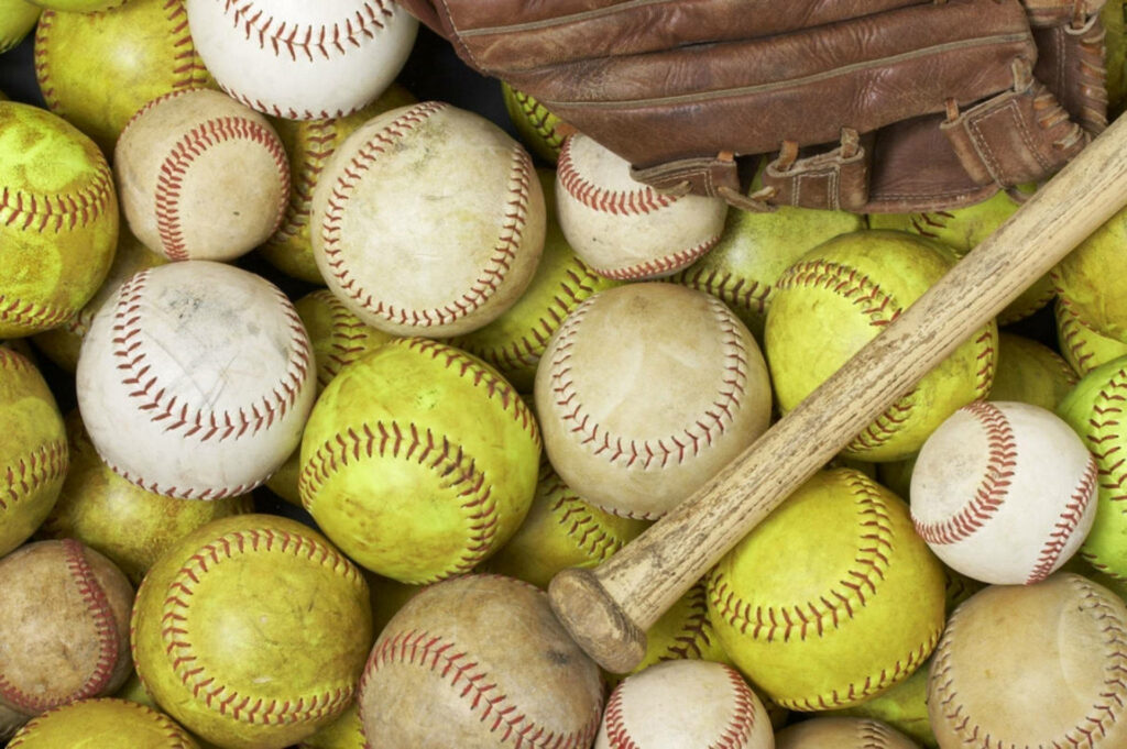 In the Realm of Adorable Softballs: A Captivating Background Image featuring an Ensemble of Bats and Gloves Wallpaper
