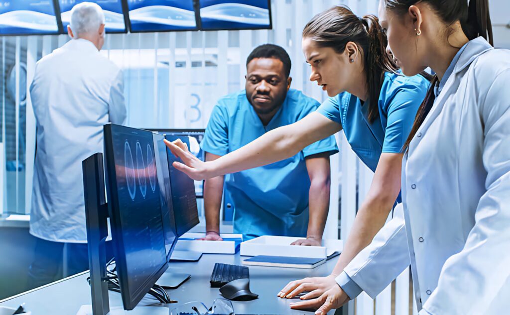 Medical team analyzing patient data on high-tech monitors in modern clinical setting with blue tones Wallpaper