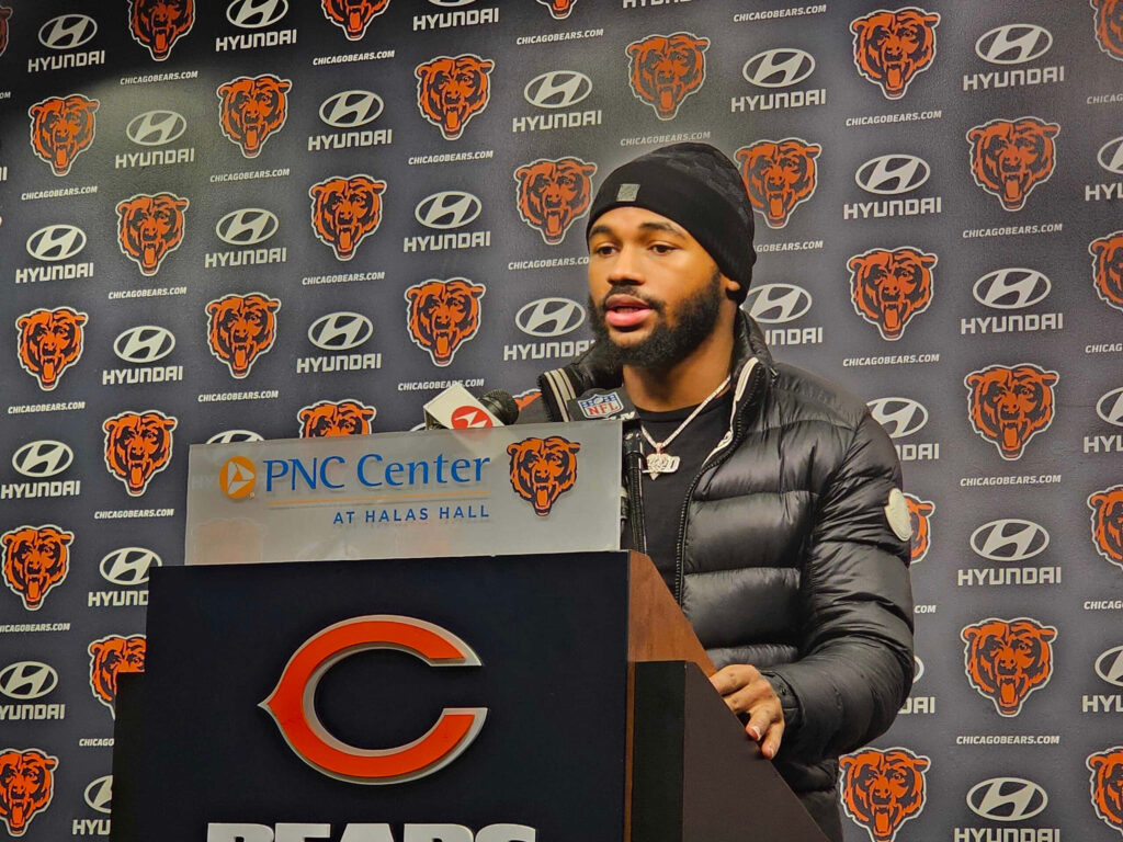 DAndre Swift at Chicago Bears press conference wearing black puffer jacket and beanie with logo backdrop Wallpaper
