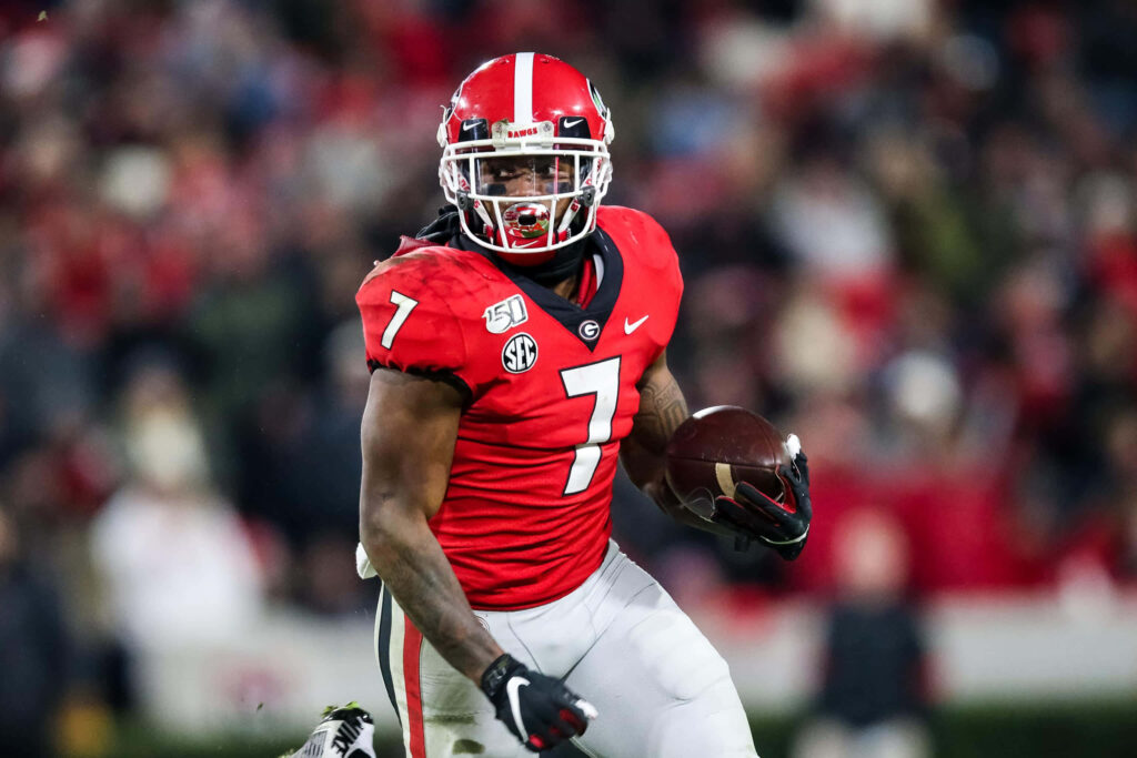 DAndre Swift sprinting in red Georgia Bulldogs uniform intense football action stadium lights Wallpaper