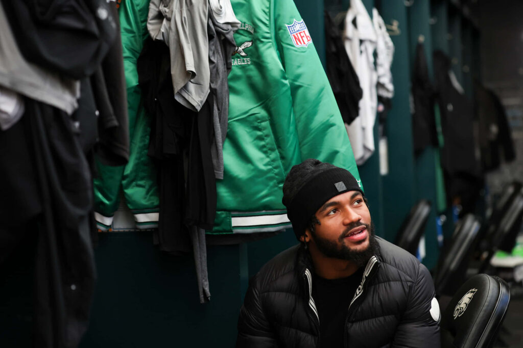 DAndre Swift in locker room reflecting surrounded by green team jackets and football gear Wallpaper