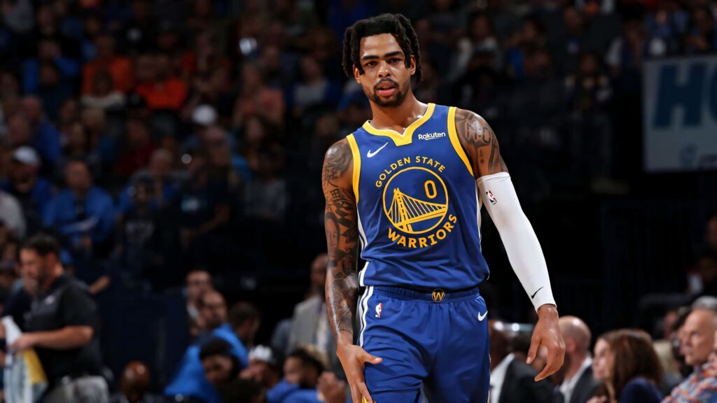 DAngelo Russell walking confidently on basketball court in Golden State Warriors blue gold jersey Wallpaper