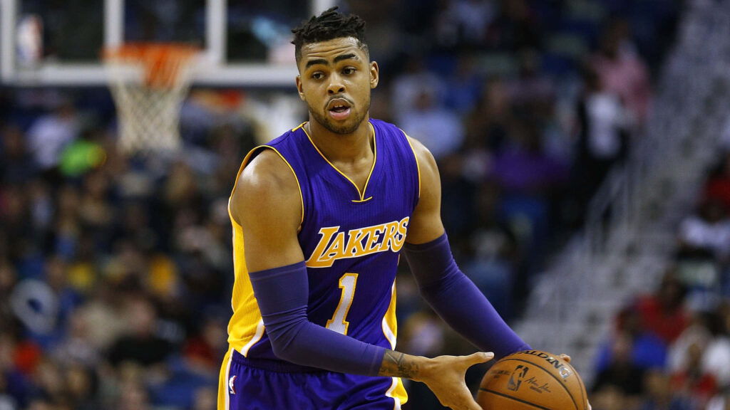 DAngelo Russell dribbling in Lakers uniform on court focused with blurred crowd background Wallpaper