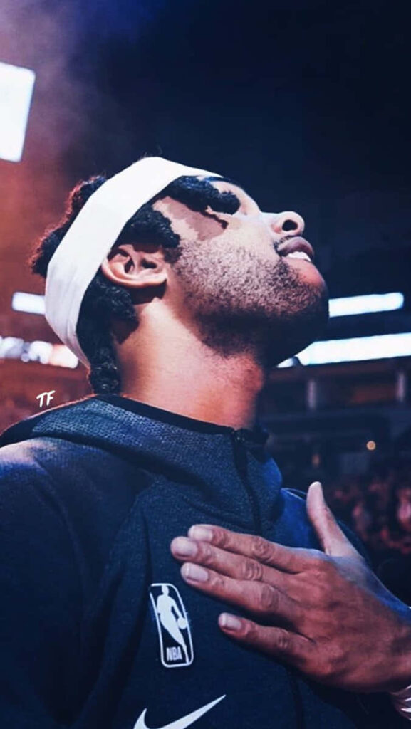 NBA All-Star D’Angelo Russell focused intense pose with warm arena lights and blue hoodie background Wallpaper
