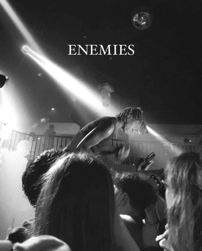 Black and white wallpaper of rapper DC The Don performing on stage with ENEMIES sign and crowd