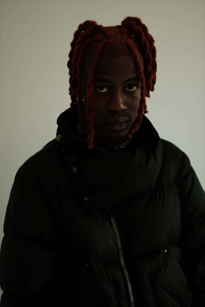 DC The Don moody portrait with red twisted hair dark puffer jacket neutral background wallpaper