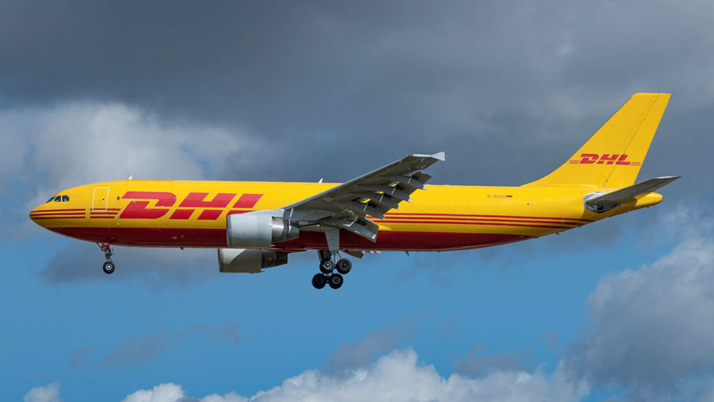 DHL Airbus cargo plane in vibrant yellow and red livery flying through dramatic cloudy sky wallpaper