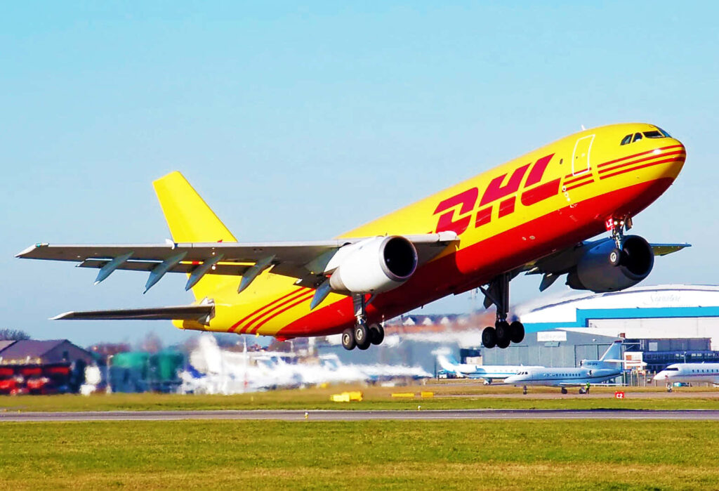 DHL cargo plane in yellow and red taking off from airport showing fast global shipping Wallpaper