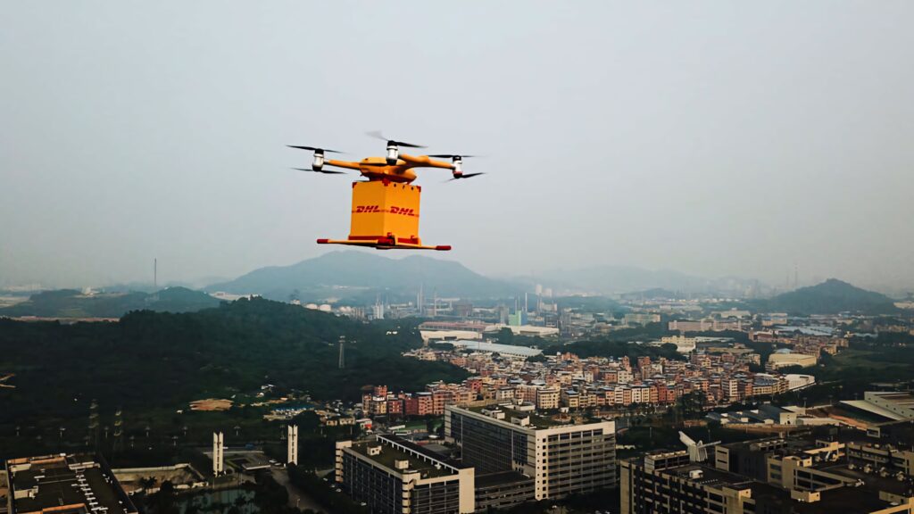 DHL yellow delivery drone flying over cityscape with hills showcasing futuristic logistics technology Wallpaper